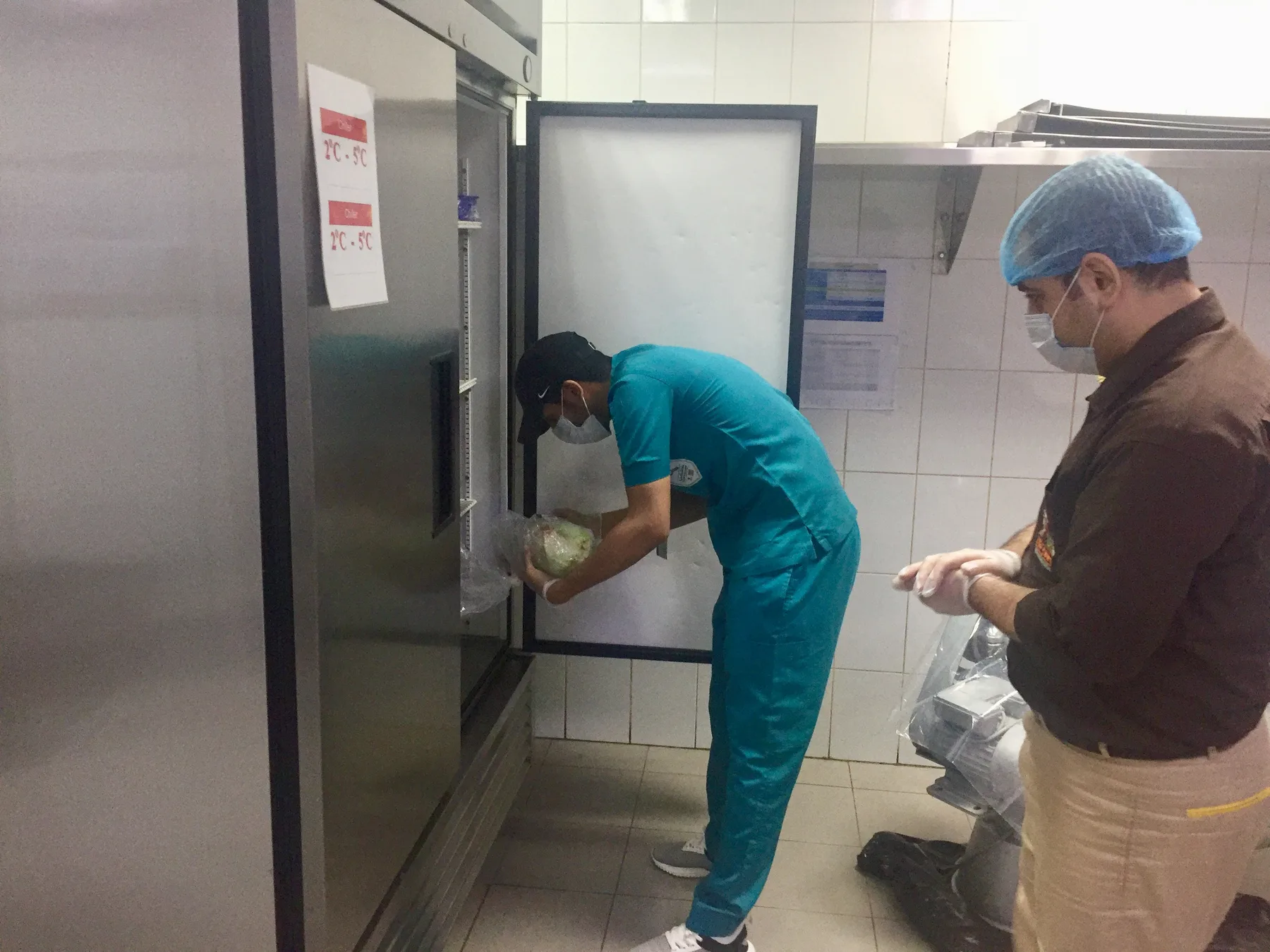 A health inspector checks food stored in a restaurant's walk-in refrigerator.