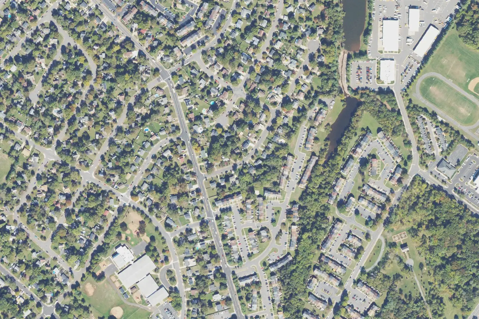 An aerial view of Point of Woods in Manassas, with detached homes on the left, townhouse courts on the right and Weems Elementary at lower left.